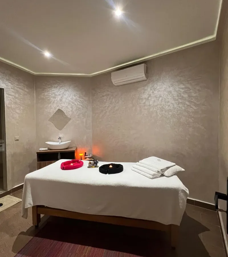 Cabine de massage à la lumière tamisée, table dressée de serviettes et bougies allumées – H2O Spa Casablanca