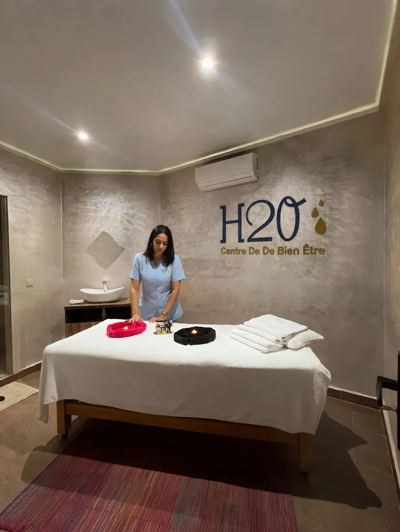 Thérapeute en tunique bleue installant la table de massage d’une cabine H2O Spa à Casablanca
