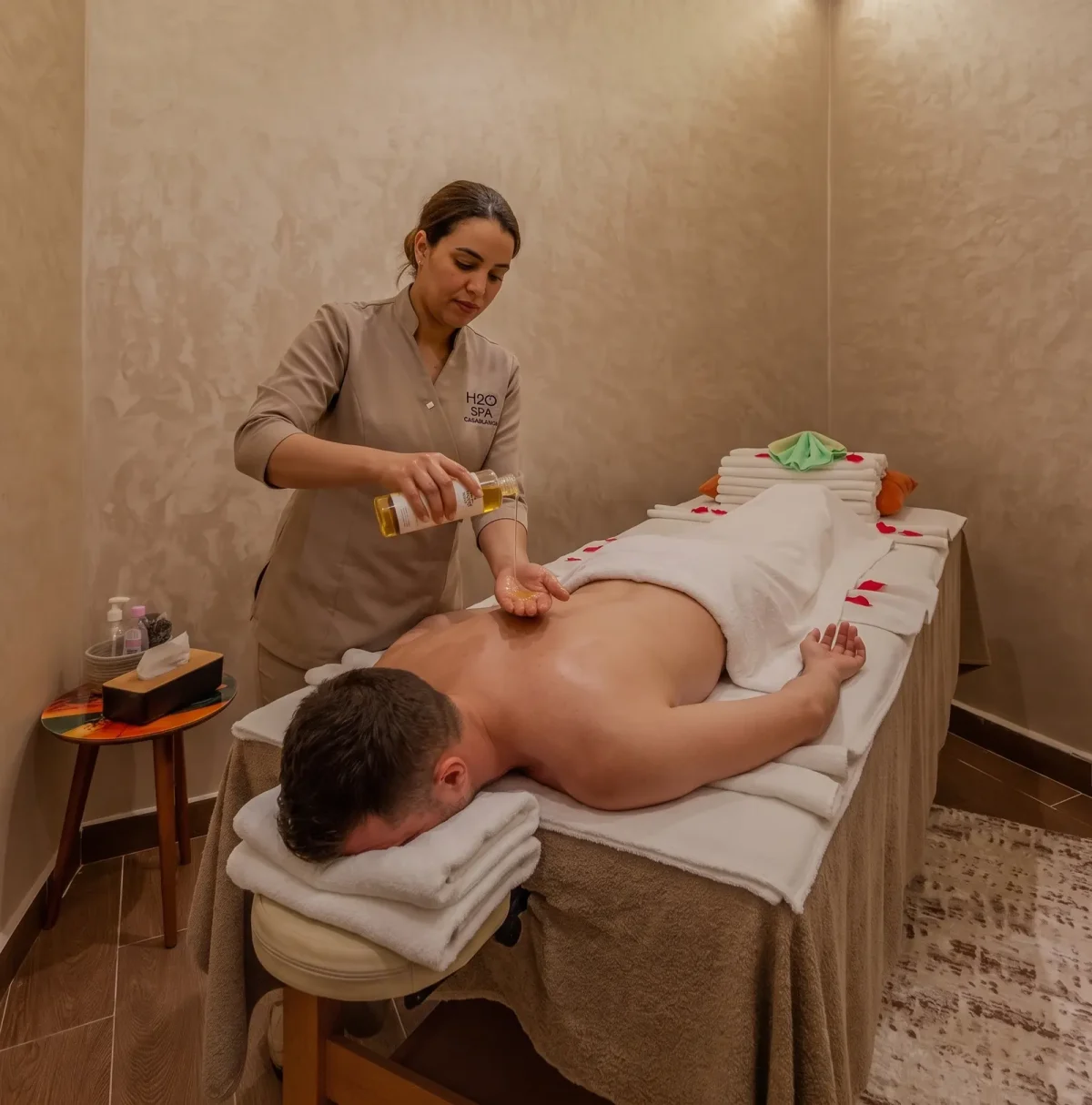 Thérapeute versant de l’huile dans sa main avant un massage du dos en cabine – H2O Spa Casablanca